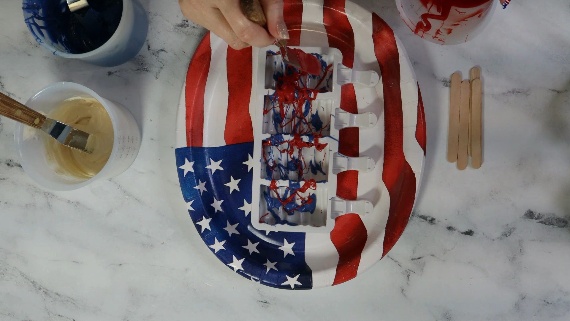 make firework fourth of july cakesicles by splattering chocolate in red white and blue in the silicone pop mold