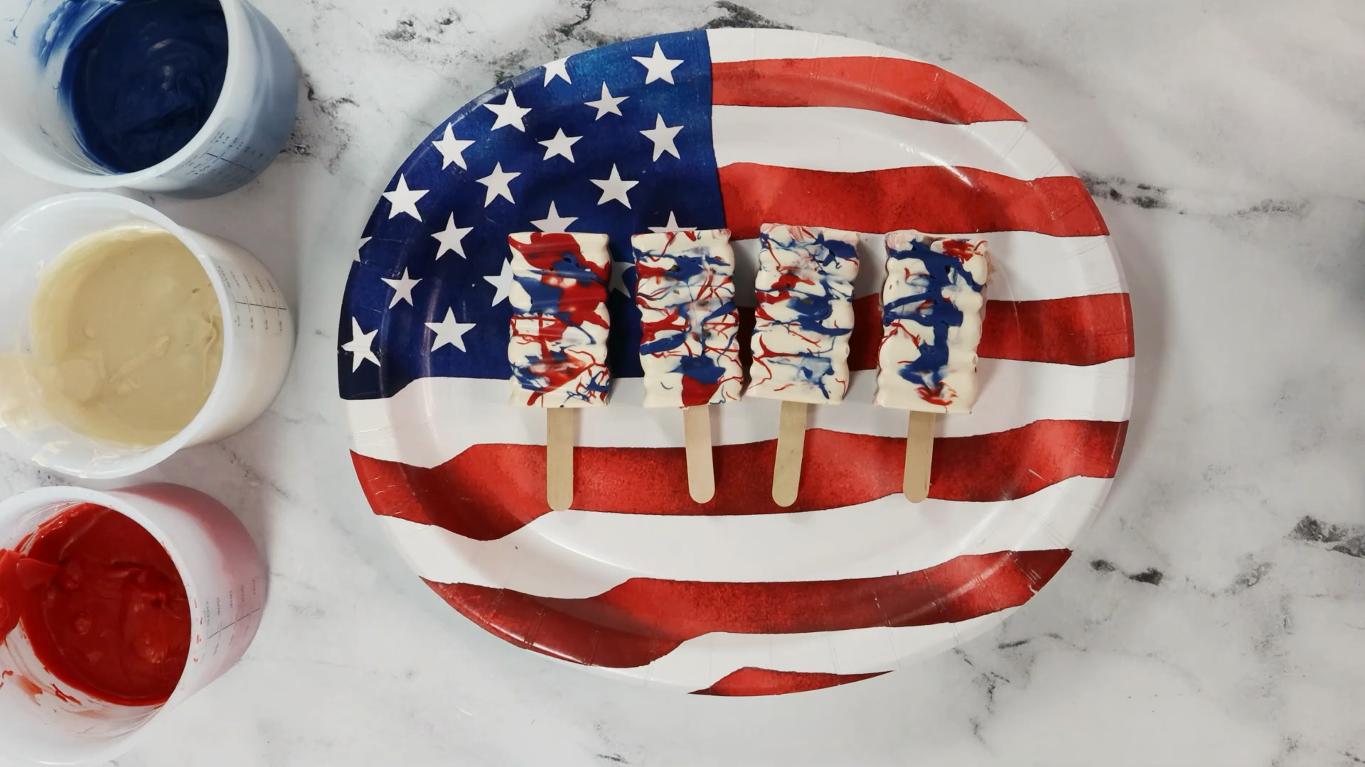 splatter painted fourth of july cakesicles in red white and blue look like fireworks